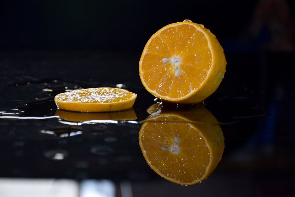 Close-up of juicy orange slices reflecting on a wet, glossy surface, capturing freshness and vibrancy.
