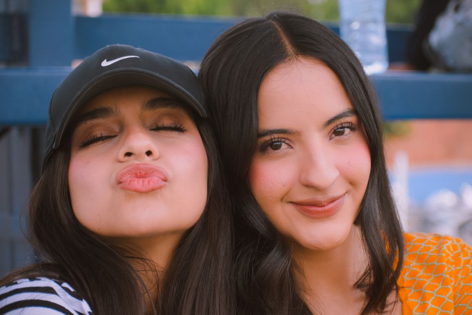 Two young women smiling and enjoying a sunny day outdoors. Relaxed and joyful atmosphere.