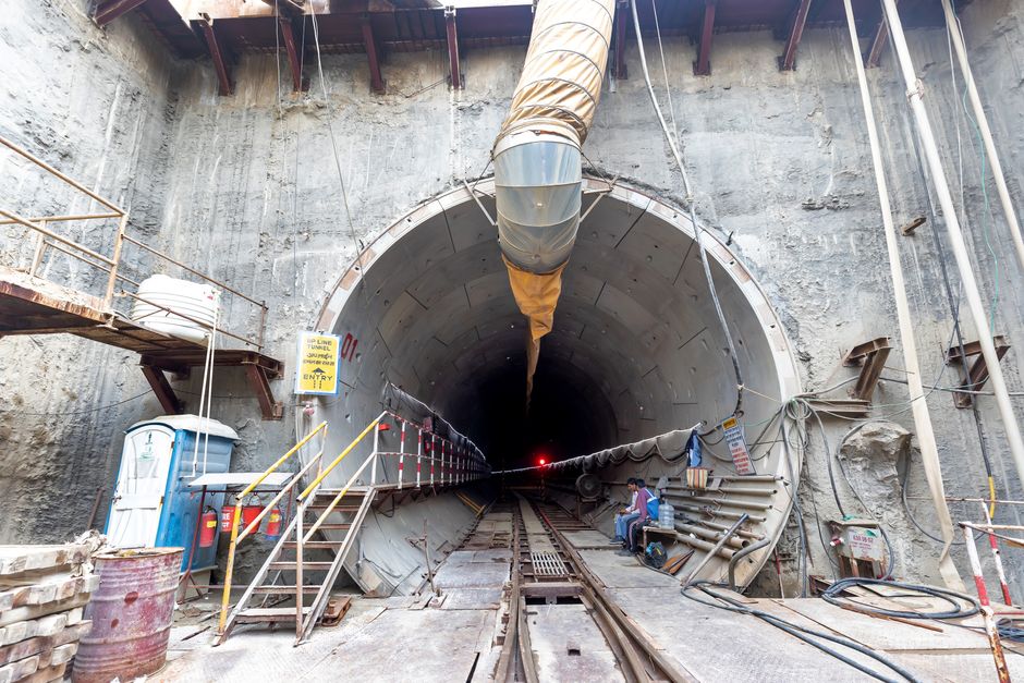 Industrial tunnel entrance under construction with heavy machinery and safety equipment.