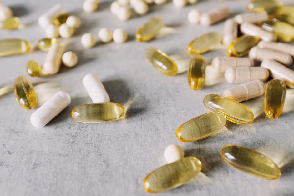 Close-up of assorted capsules and pills spread across a gray surface, capturing diverse pharmaceutical forms.