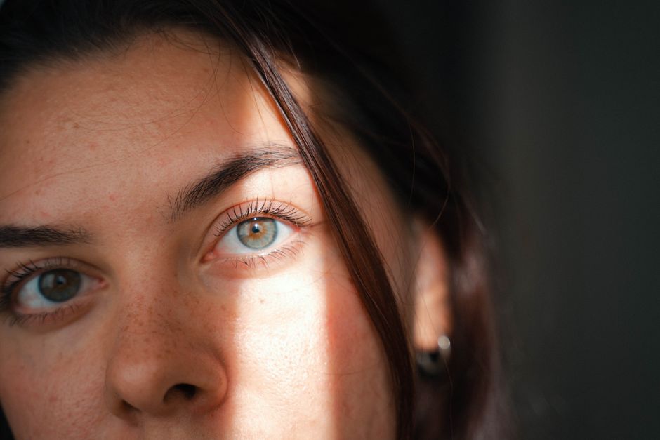 Intimate close-up of a woman's face with soft natural lighting, emphasizing features.