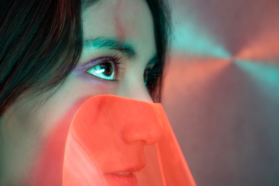 Close-up artistic portrait of a woman with vivid neon lighting and abstract elements.