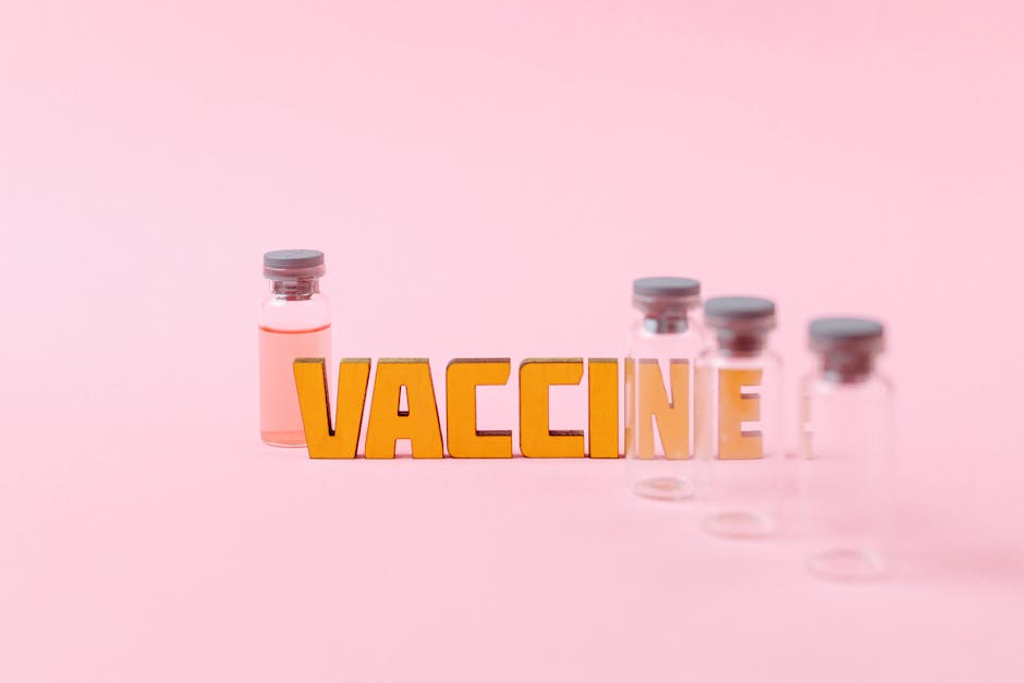 Conceptual image of vaccine vials with bold 'VACCINE' text on a pink background.