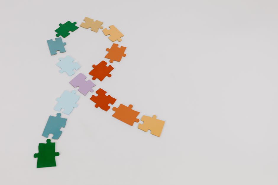 Colorful puzzle pieces forming a ribbon shape on a white background, symbolizing awareness.