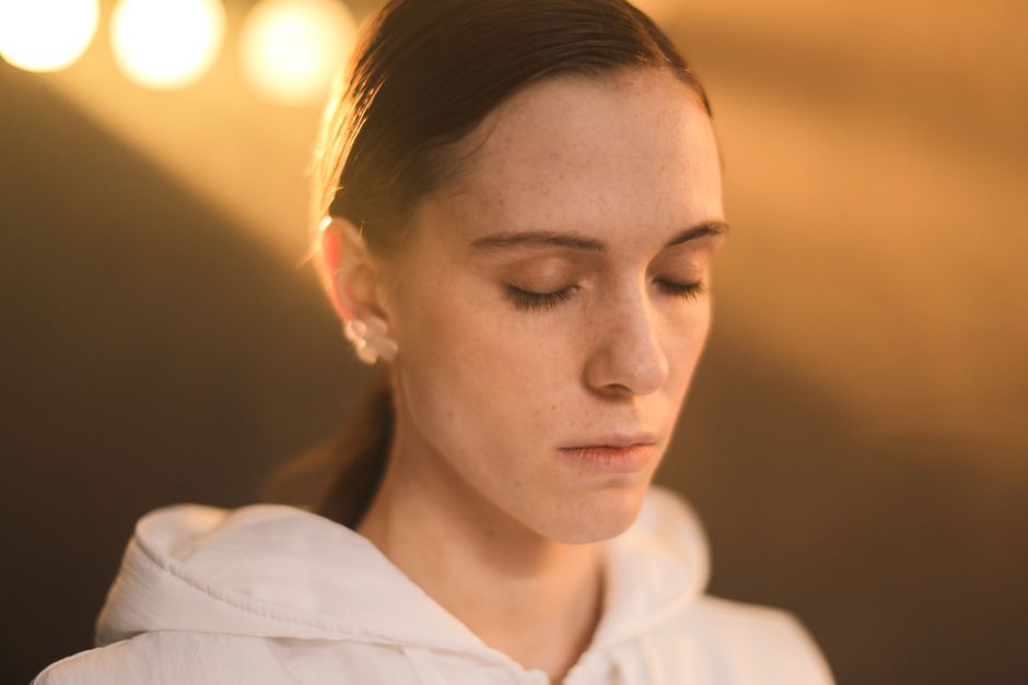 Close-up of a serene woman with closed eyes, basking in warm sunlight.