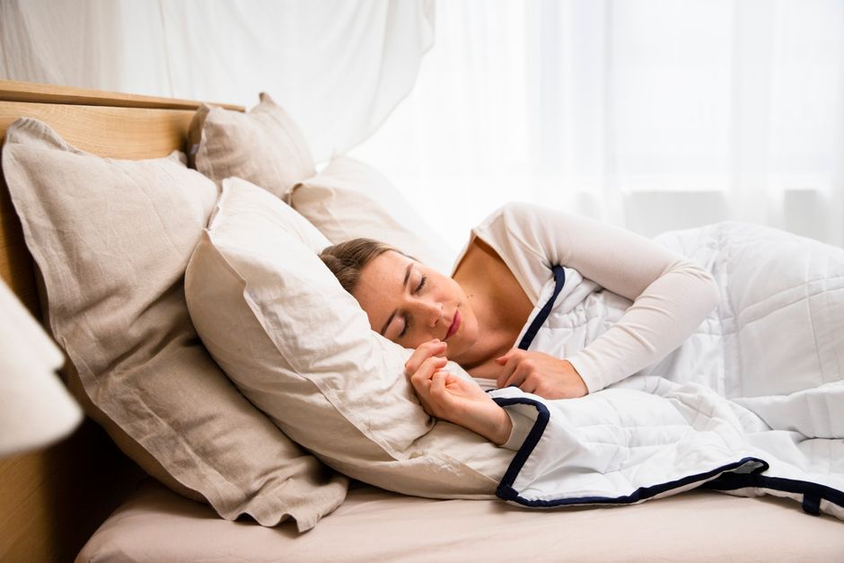 Caucasian woman peacefully sleeping in a cozy bed with pillows and duvet.