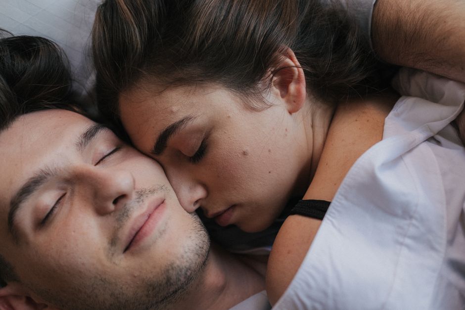 A close-up of an intimate couple cuddling and resting together in bed.