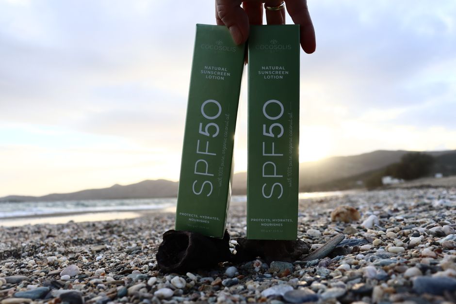 SPF 50 sunscreen bottles on a rocky beach at sunset, offering sun protection and skincare benefits.
