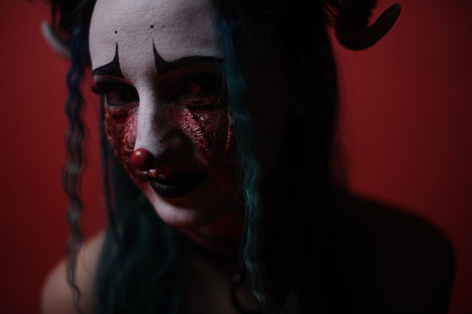 A dramatic portrait of a character with theatrical makeup in a moody, dark setting.