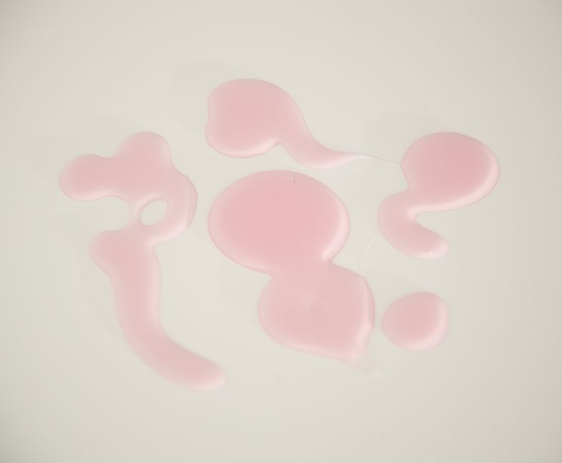 Overhead view of abstract backdrop of wavy liquid flows and drops of smooth gel on white background