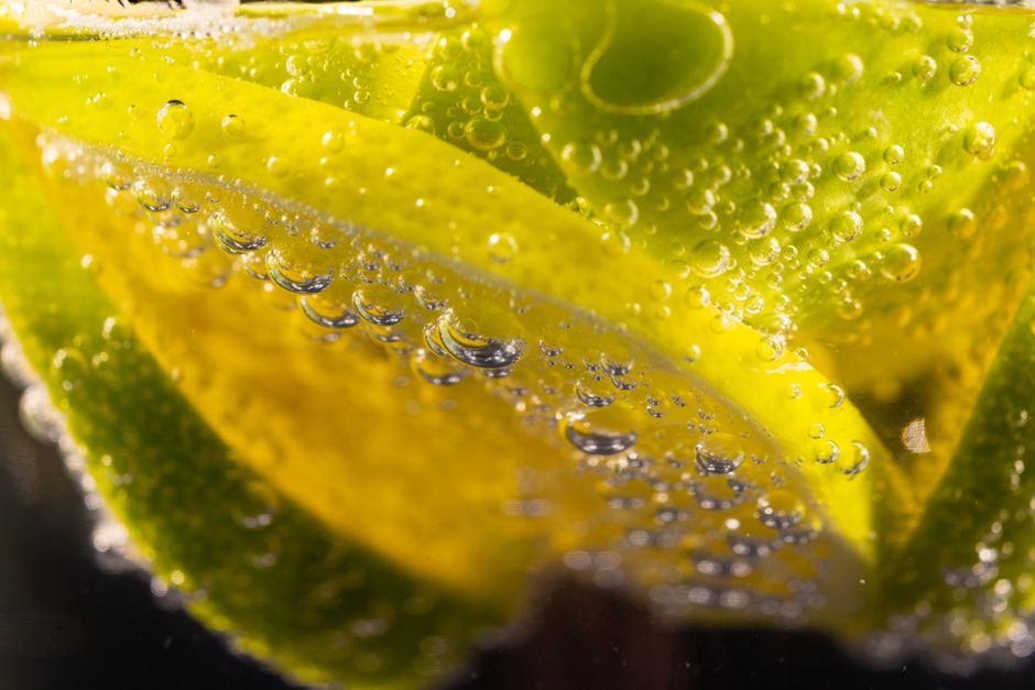 Close-up of lemon and lime slices with bubbles in a refreshing soda drink.