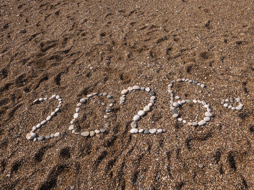 Stones arranged to form the number 2026 on a sandy coastline, creating a natural and creative scene.