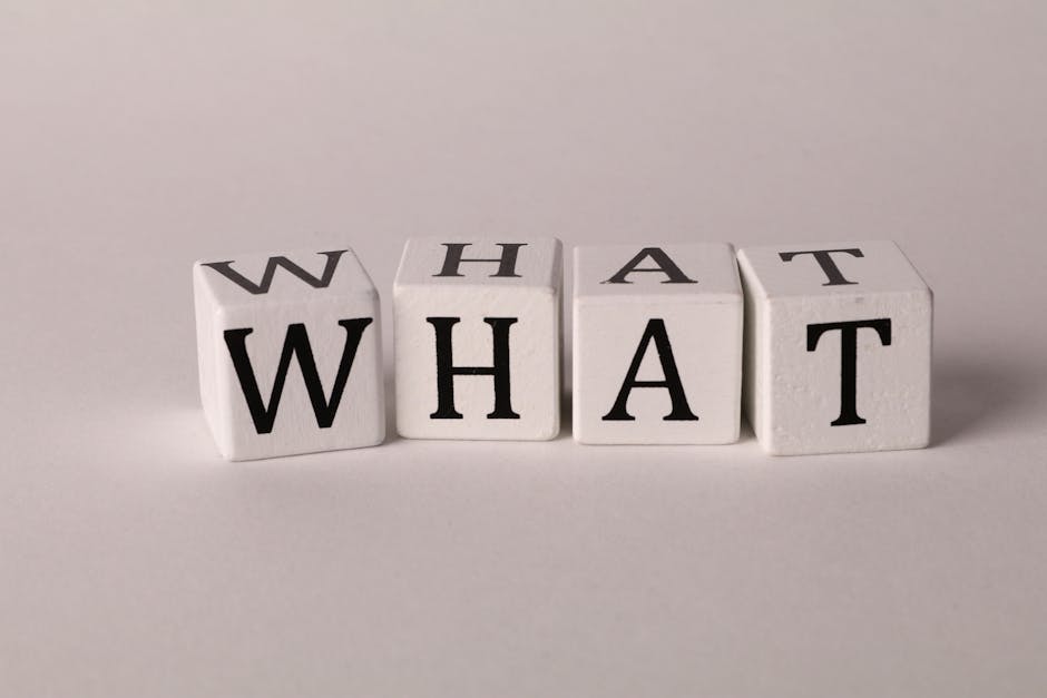 Close-up of wooden blocks with letters spelling 'What' on a white background, emphasizing curiosity and inquiry.